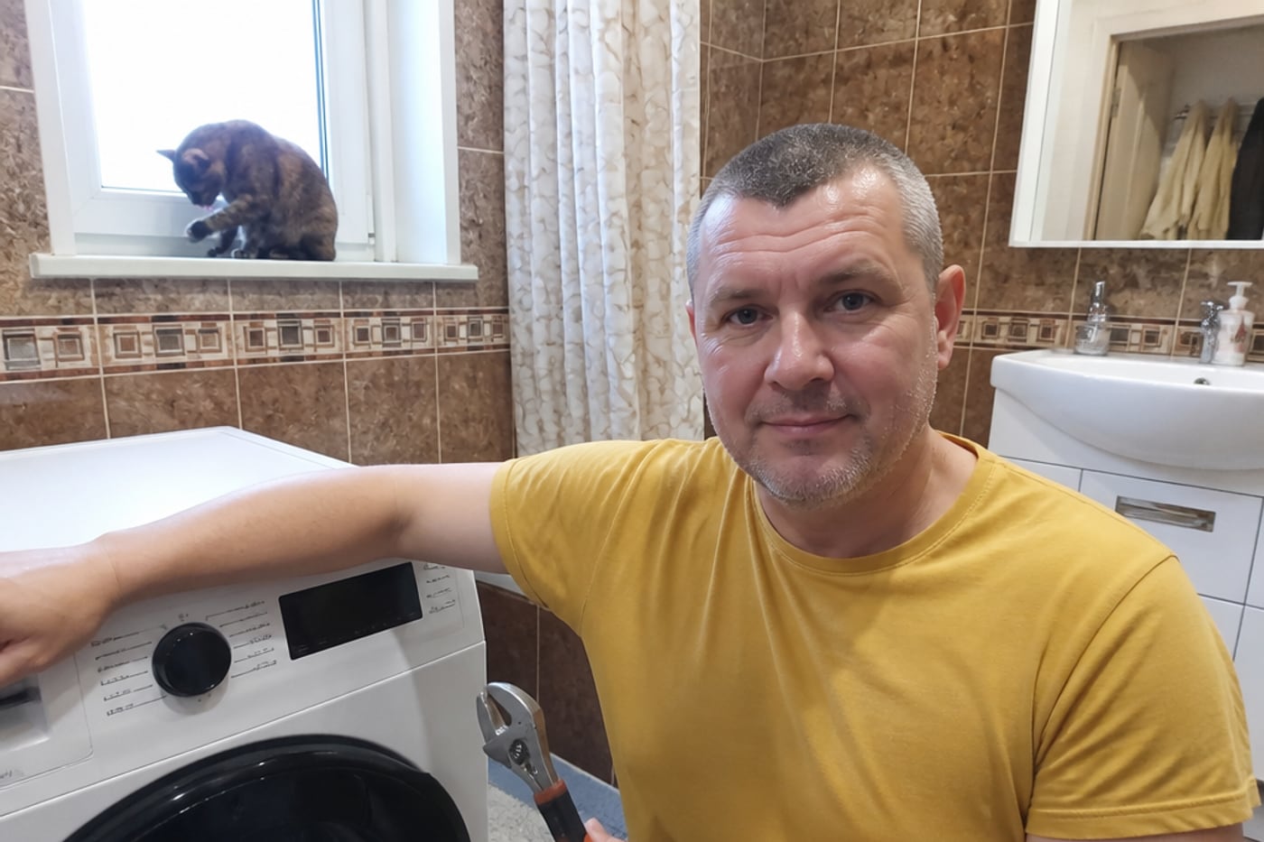 Мастер Александр со стиральной машиной, в руке гаечный ключ